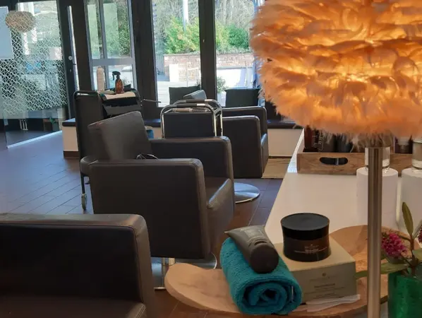 Moderner Friseursalon mit bequemen Stühlen, Kosmetikprodukten und stilvoller Beleuchtung.