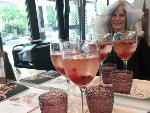 Frau im Friseursalon mit Sekt und Beeren, Gläser auf stylischem Tisch, Wohlfühlatmosphäre.