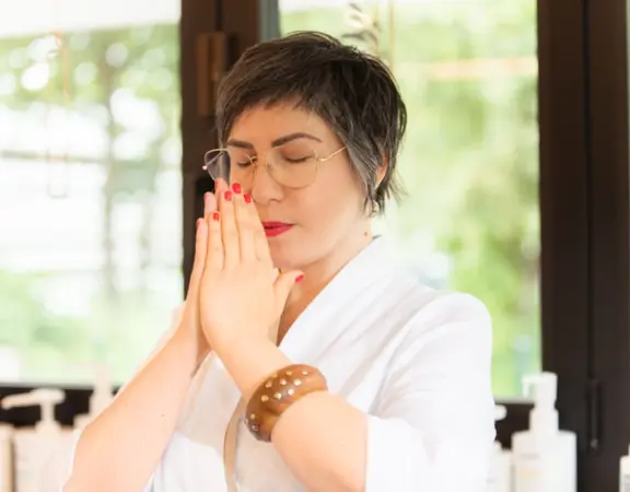 Frau mit Brille meditiert entspannt im Spa, Selbstfürsorge und Wellness im Fokus.